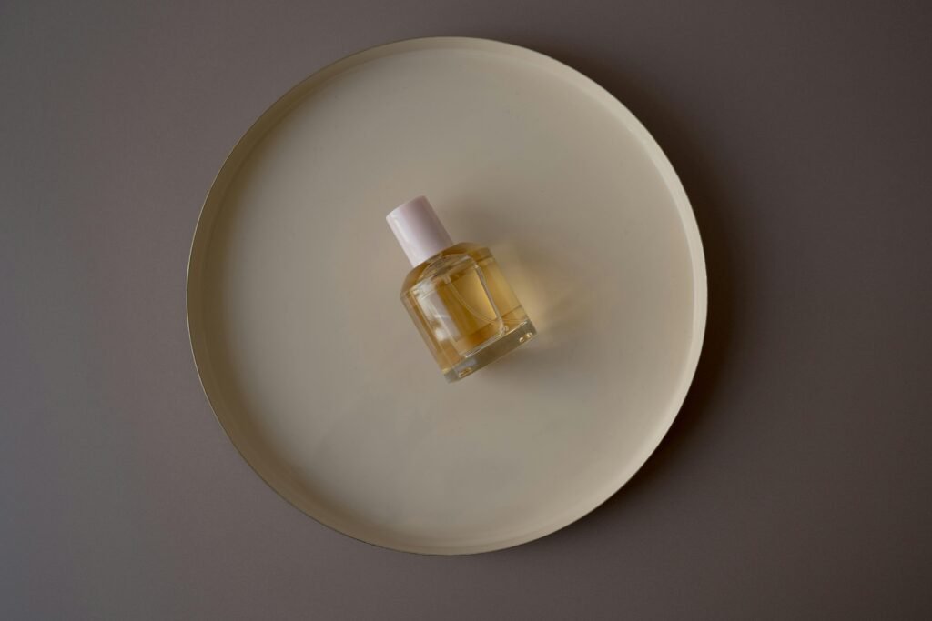 A perfume bottle elegantly placed on a beige circular tray against a gray background.